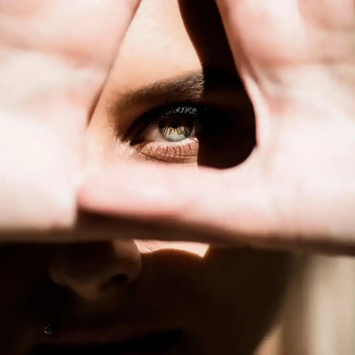 woman holding her hands around her eye