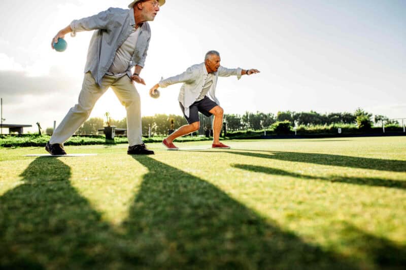 Image of two aging men playing bocce ball.